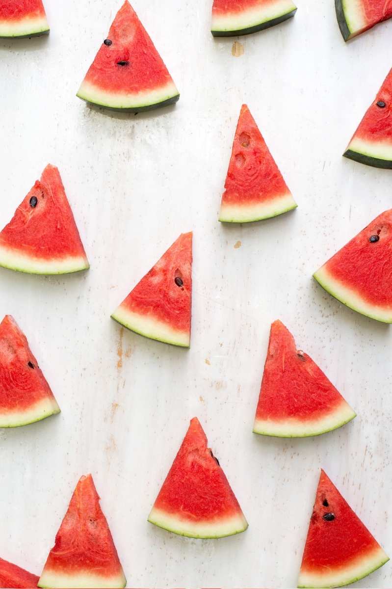 Overhead of small triangular wedges of watermelon on a countertop.