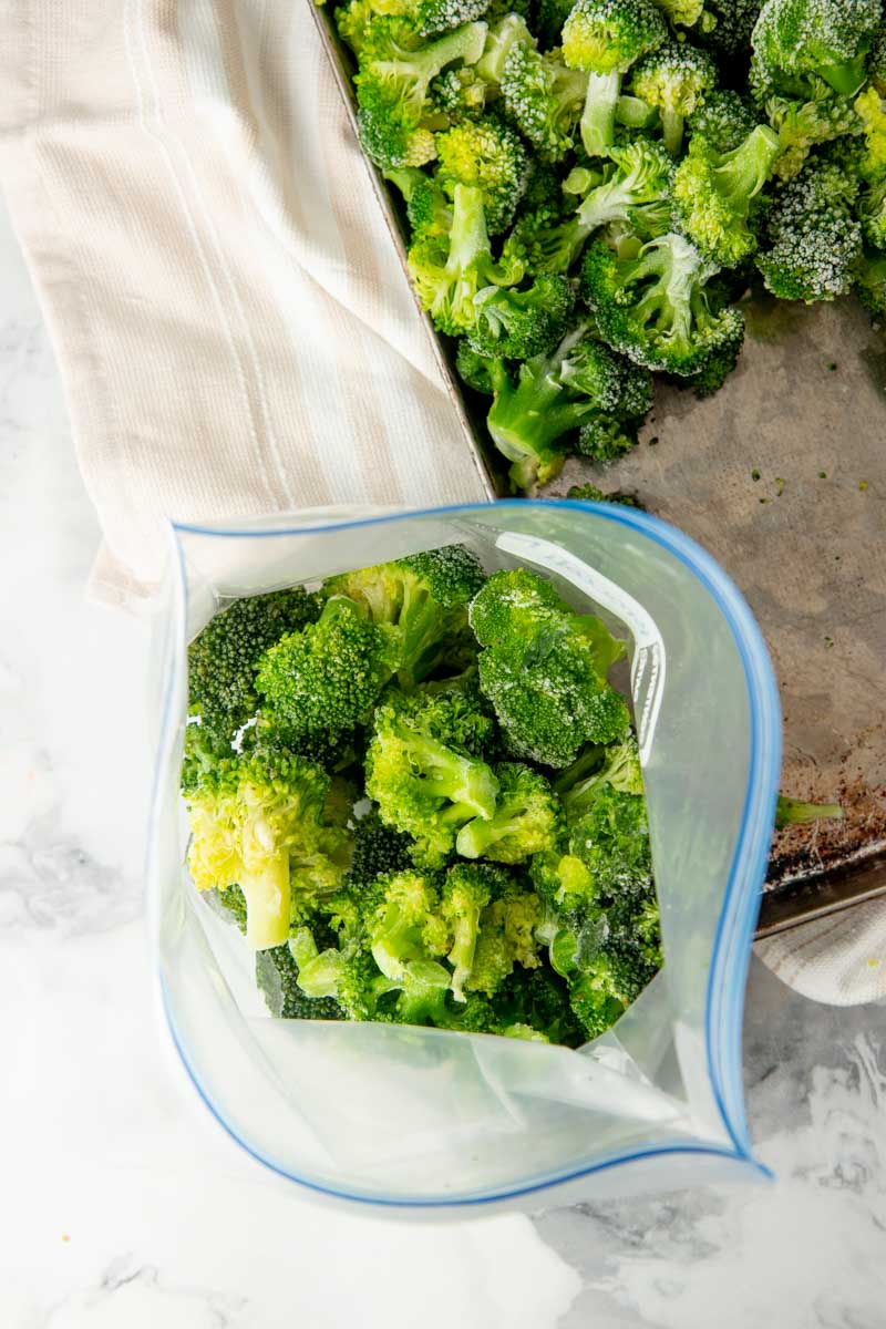 Filling a freezer bag with prepped broccoli.