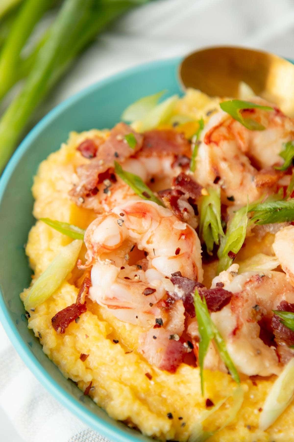 Close view of perfectly cooked shrimp on top of creamy yellow corn grits.