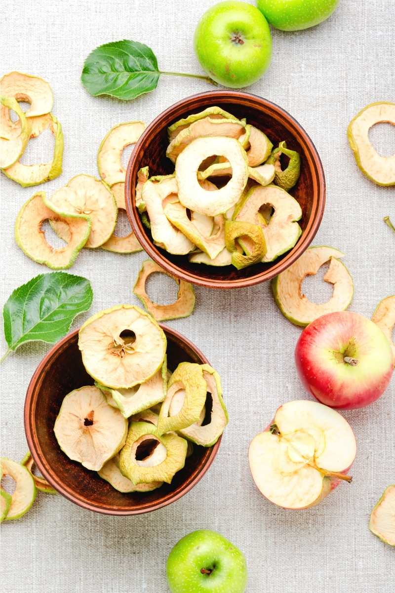 Overhead of two bowls filled with dehydrated apple rings.