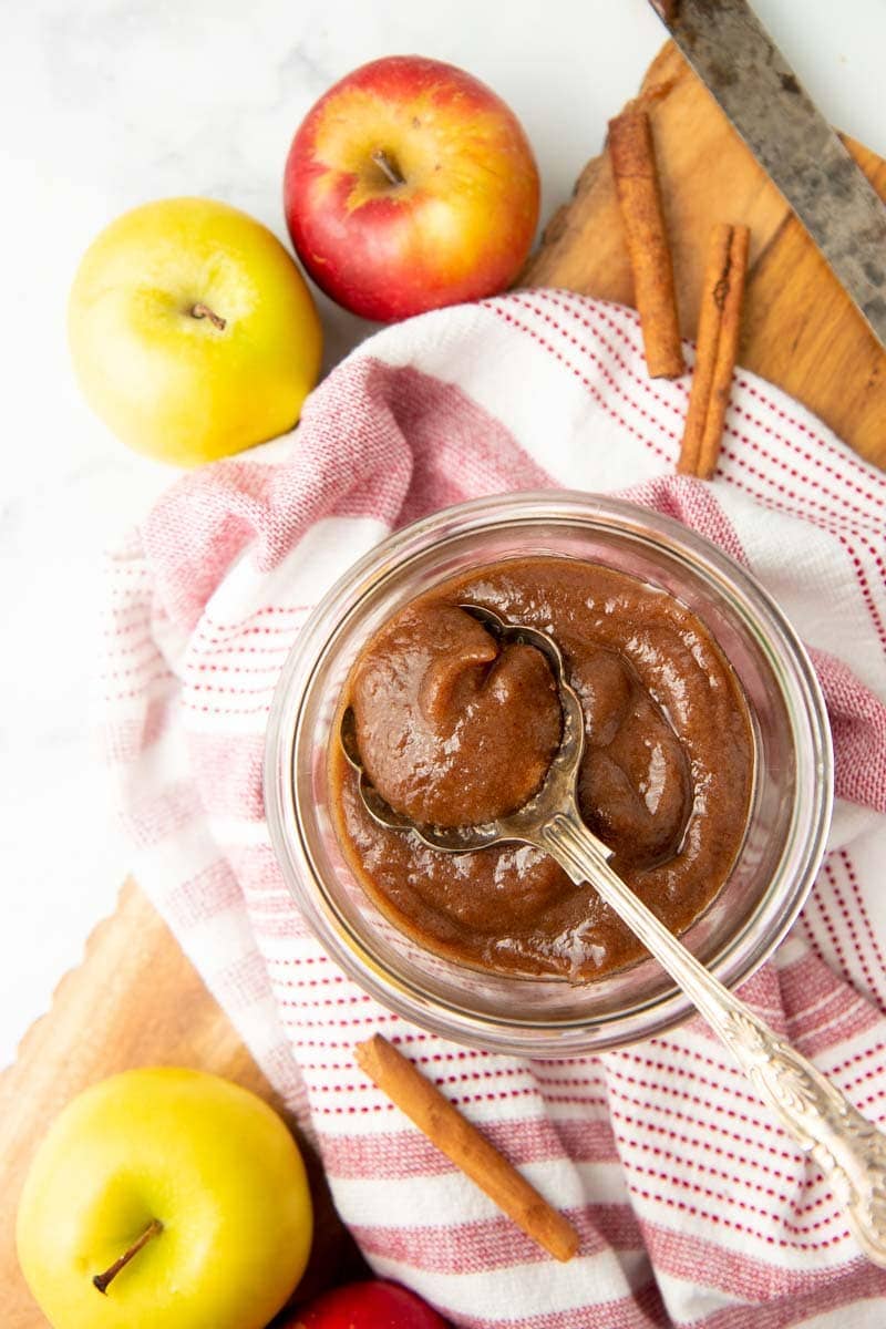 A spoon scoops homemade apple butter from a jar.