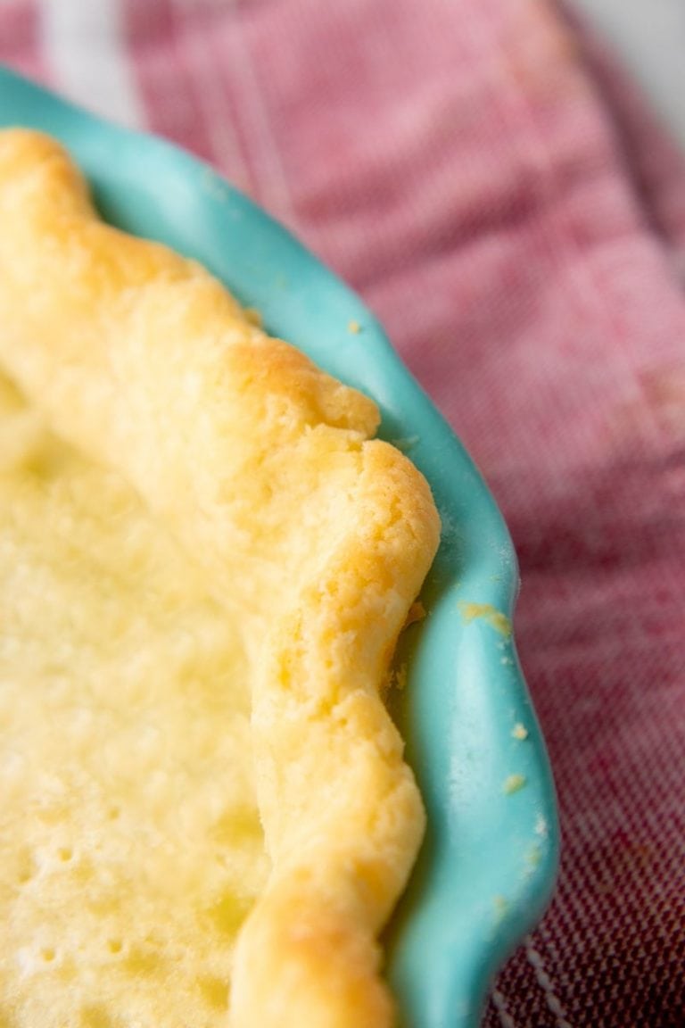 Close-up of a golden, baked edge of pie crust in a teal pie plate.