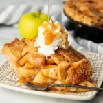 Garnished slice of caramel apple pie with extra caramel drizzling on top.