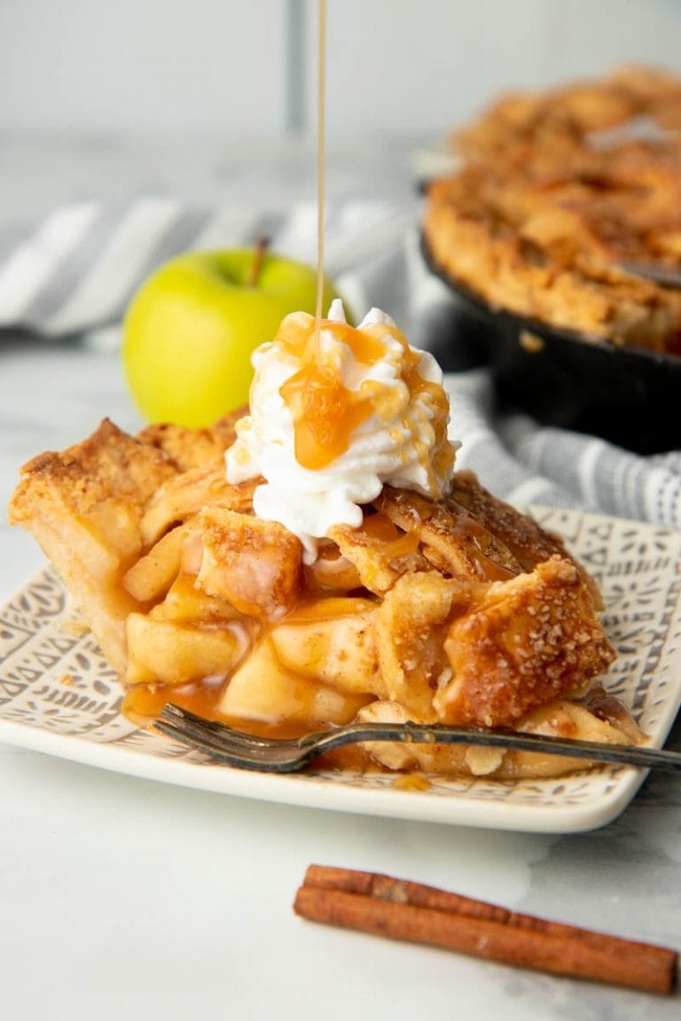 Garnished slice of caramel apple pie with extra caramel drizzling on top.