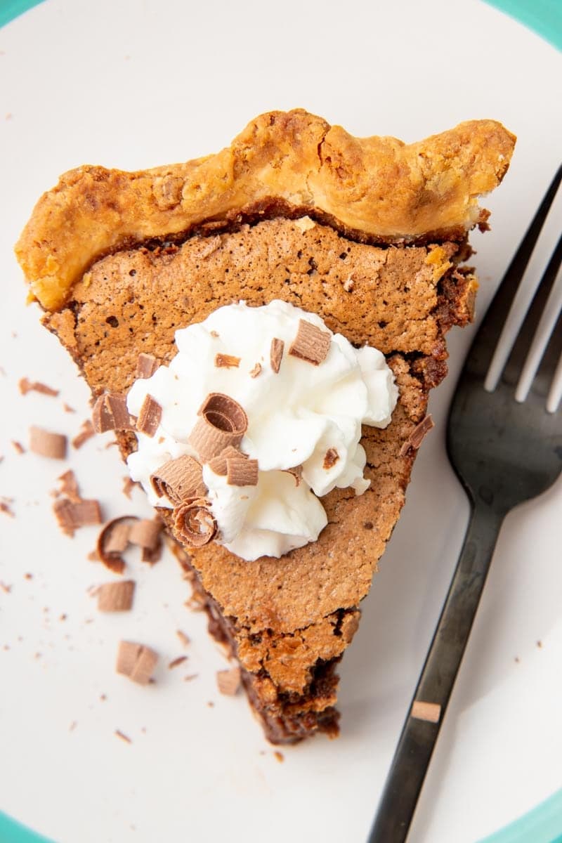 Top view of a slice of chocolate chess pie with whipped cream and chocolate shavings on top.