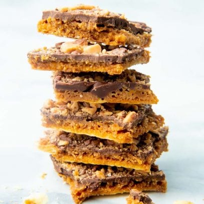 Six pieces of homemade saltine toffee stacked high on a counter.