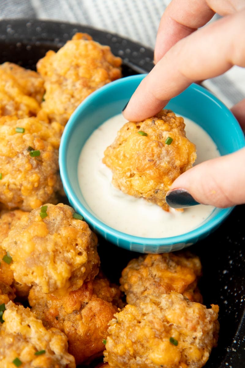 Dipping a sausage ball into ranch dressing .