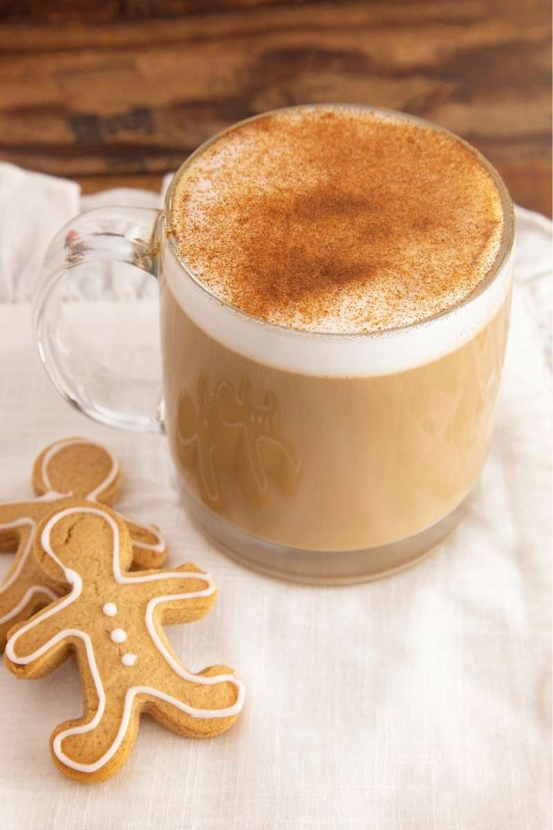 Gingerbread latte with a heavy sprinkle of cinnamon on top in a glass mug.
