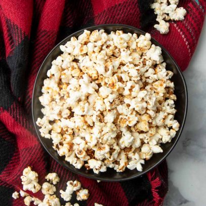 Top view of a black bowl piled high with sweet and salty popcorn.