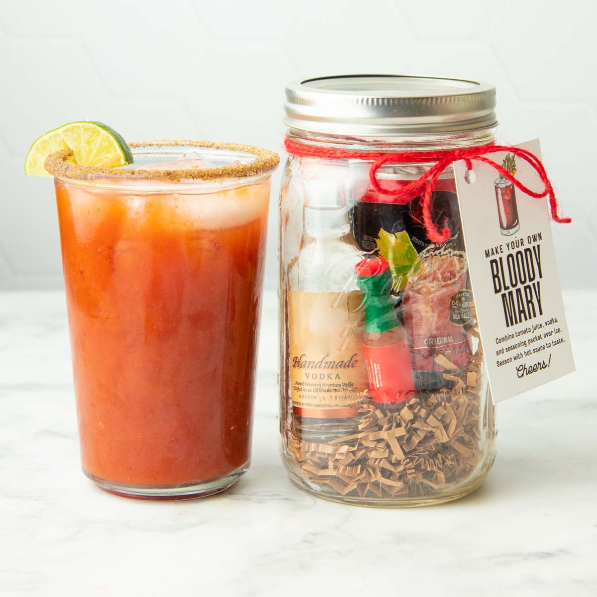 A bloody mary stands next to a diy bloody mary cocktail kit in a mason jar.