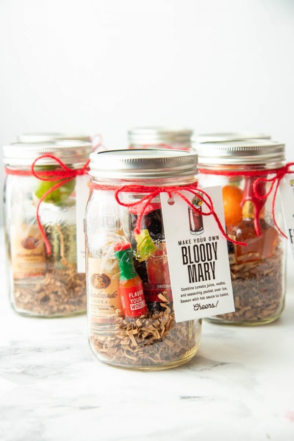 A bloody mary cocktail kits with a gift tag and red ribbon stands in front of 5 other cocktail gift kits.