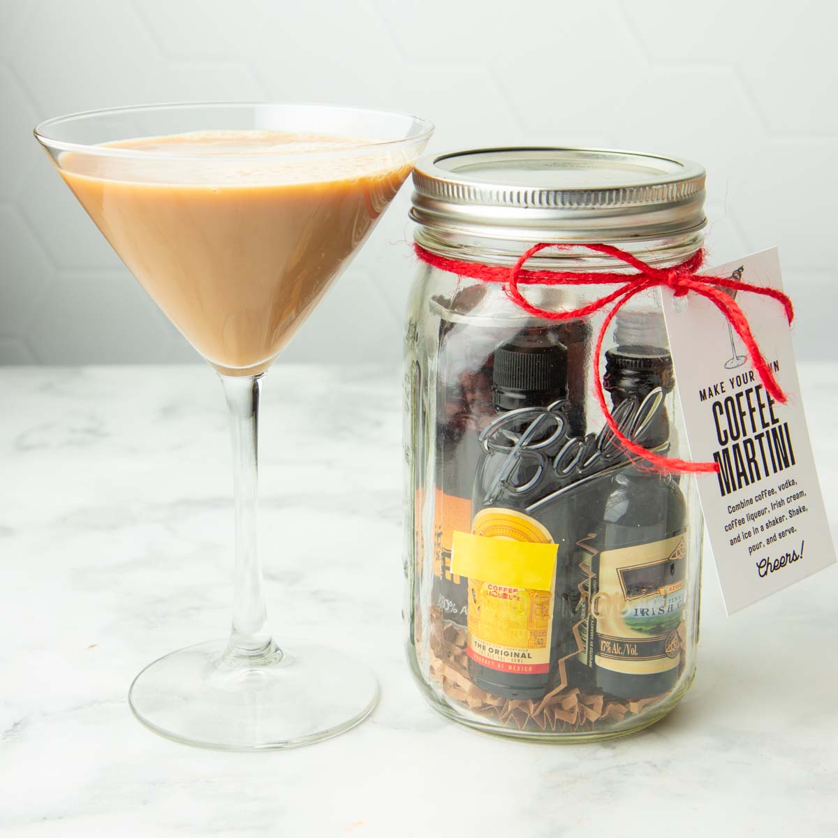 A coffee martini stands tall in a martini glass next to a diy cocktail kit in a mason jar.
