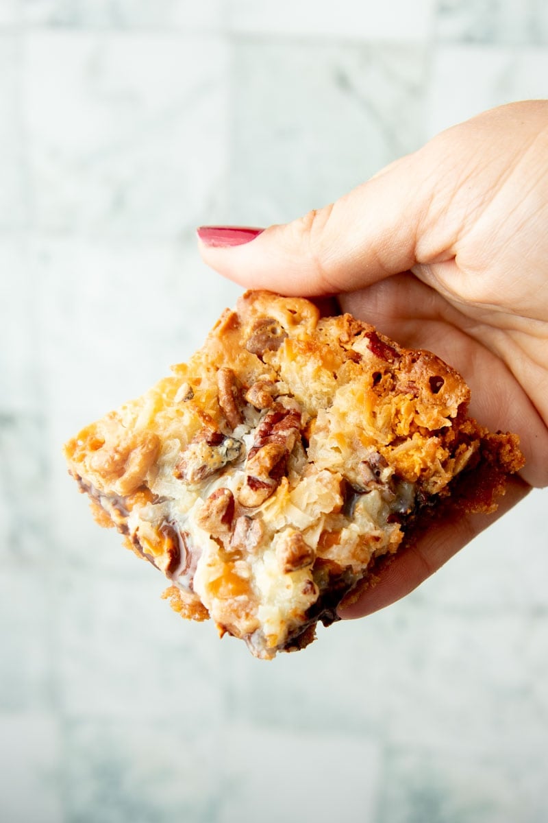 A hand holds up a magic 7 layer bar.