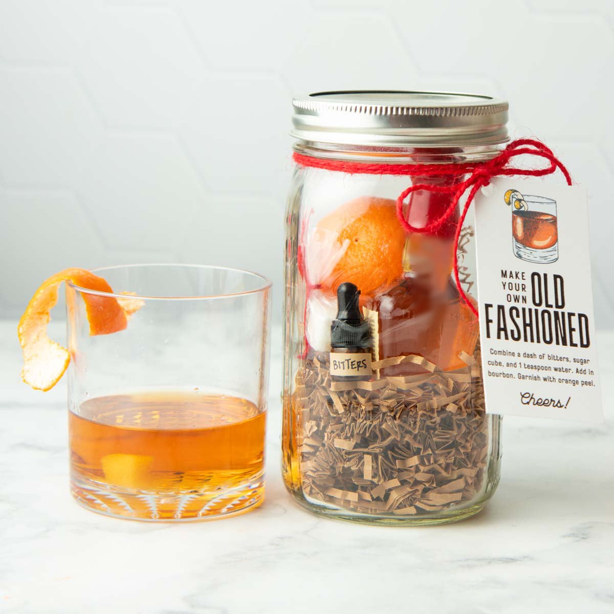 An old fashioned sits next to a make your own old fashioned cocktail kit packaged for gifting.