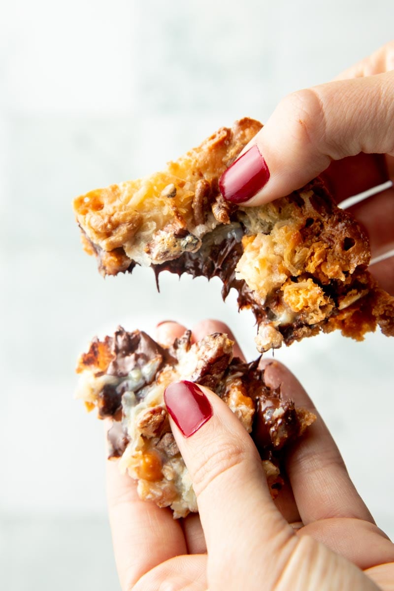 Two hands pull apart a finished bar with gooey chocolate in the center