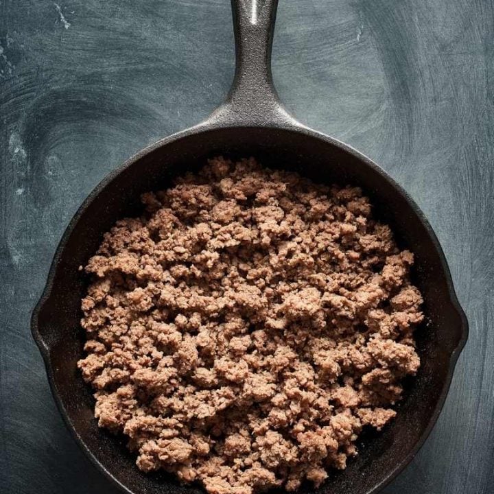 Overhead of browned mince in a cast iron skillet.