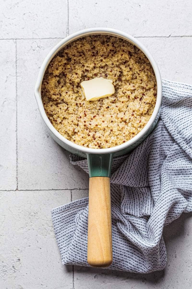 Cooked quinoa in a pot topped with butter.