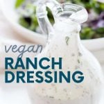 Close view of homemade coconut milk ranch dressing in a glass cruet with a salad in the background. A text overlay reads, "Easy. Healthy. Cheap. Vegan Ranch Dressing."