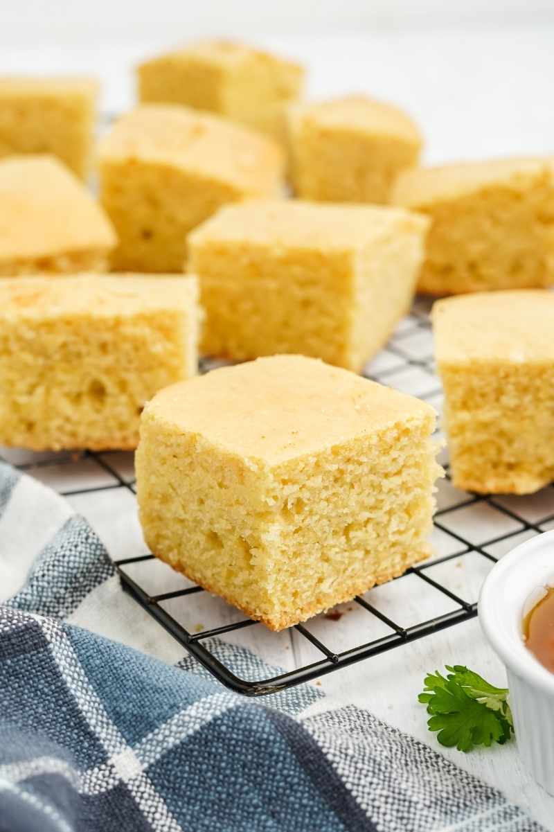 Close view of fluffy squares of buttermilk cornbread on a cooling rack.
