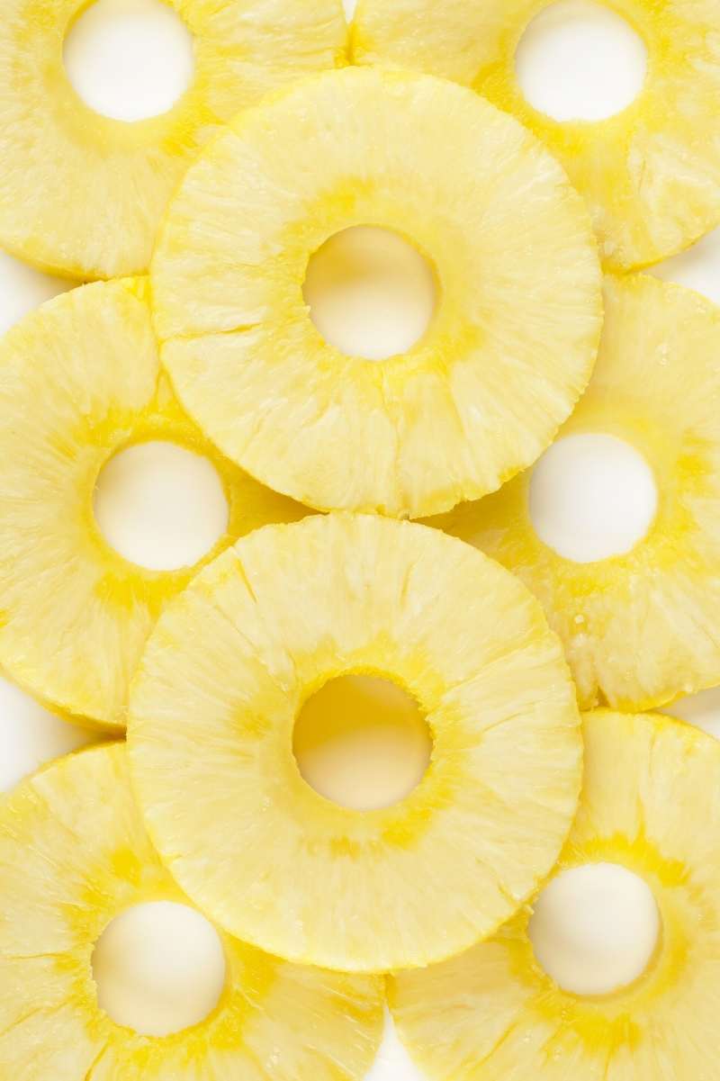 Overhead of pineapple rings arranged two by two on a counter with two more rings on top.