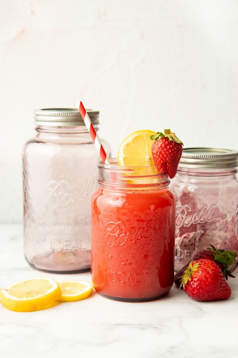 A full jar of lemonade in front of two empty jars