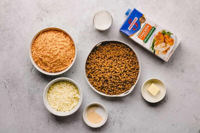 Overhead of ingredients needed to make instant pot macaroni and cheese., including macaroni, broth, and cheese