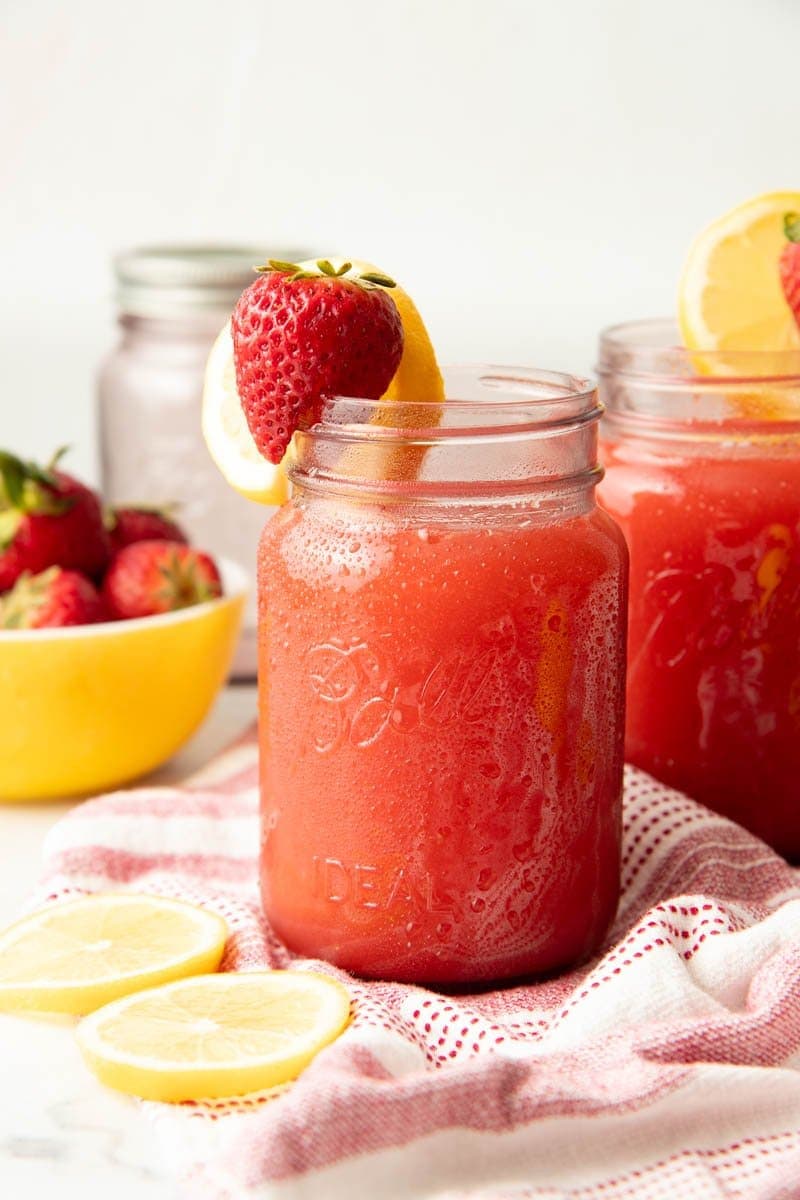 Close up on a jar full of a pink drink, garnished with fruit