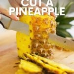 A knife cuts the rind off a pineapple. A text overlay reads "How to Cut a Pineapple"