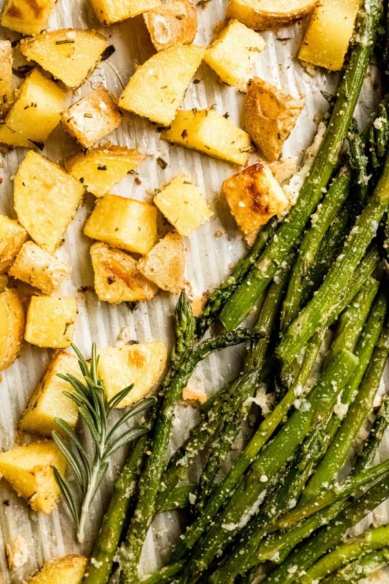 Roasted rosemary potatoes and asparagus on a sheet pan close up.