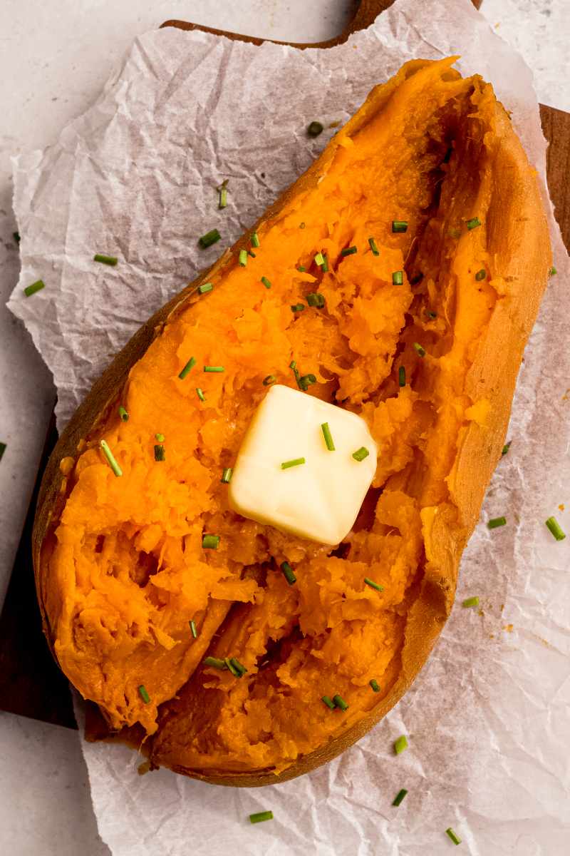 Top view of an instant pot cooked sweet potato, split and topped with a pat of butter.