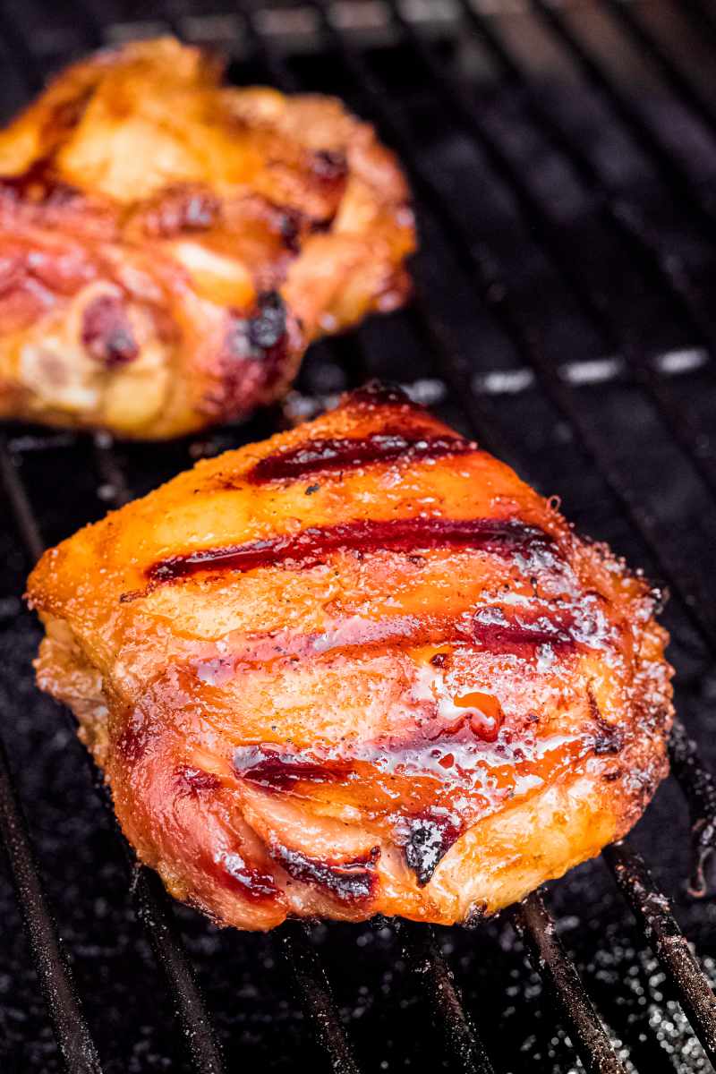 Close view of chicken thighs cooking on a gas grill.