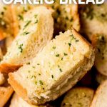 Close view of a pile of roasted garlic bread slices in a bread basket. A text overlay reads, "Roasted Garlic Bread."