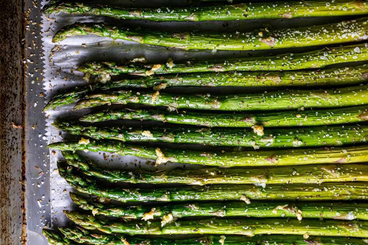 Roasted asparagus spears on a baking sheet lined with parchment paper.