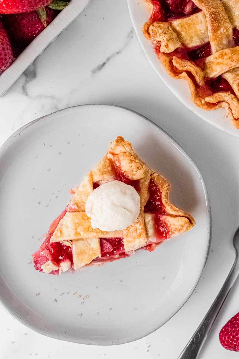 Birdseye view of a slice of strawberry rhubarb pie served a la mode with a small scoop of vanilla ice cream.
