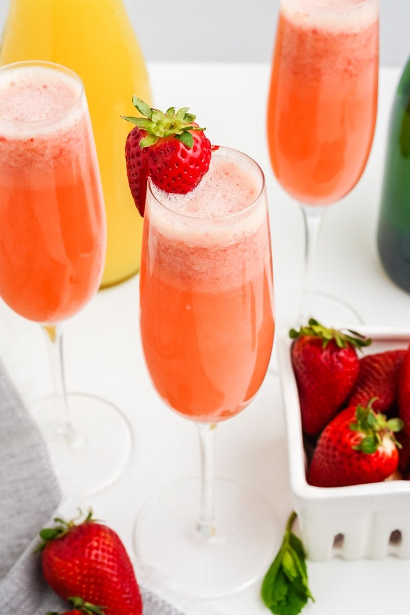 Close view of three pink mimosas with bright red strawberries around.