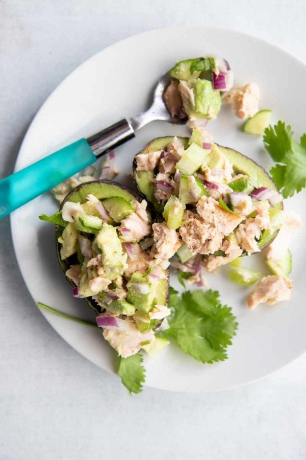 Birdseye view of a lunch serving of tuna salad with avocado, celery, cucumber, and red onion in two avocado halves.