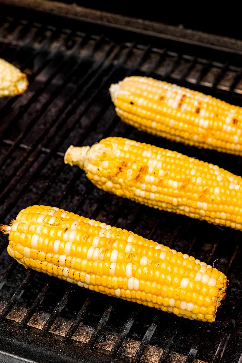 Close view of sweet corn on the cob cooking on grill grates.