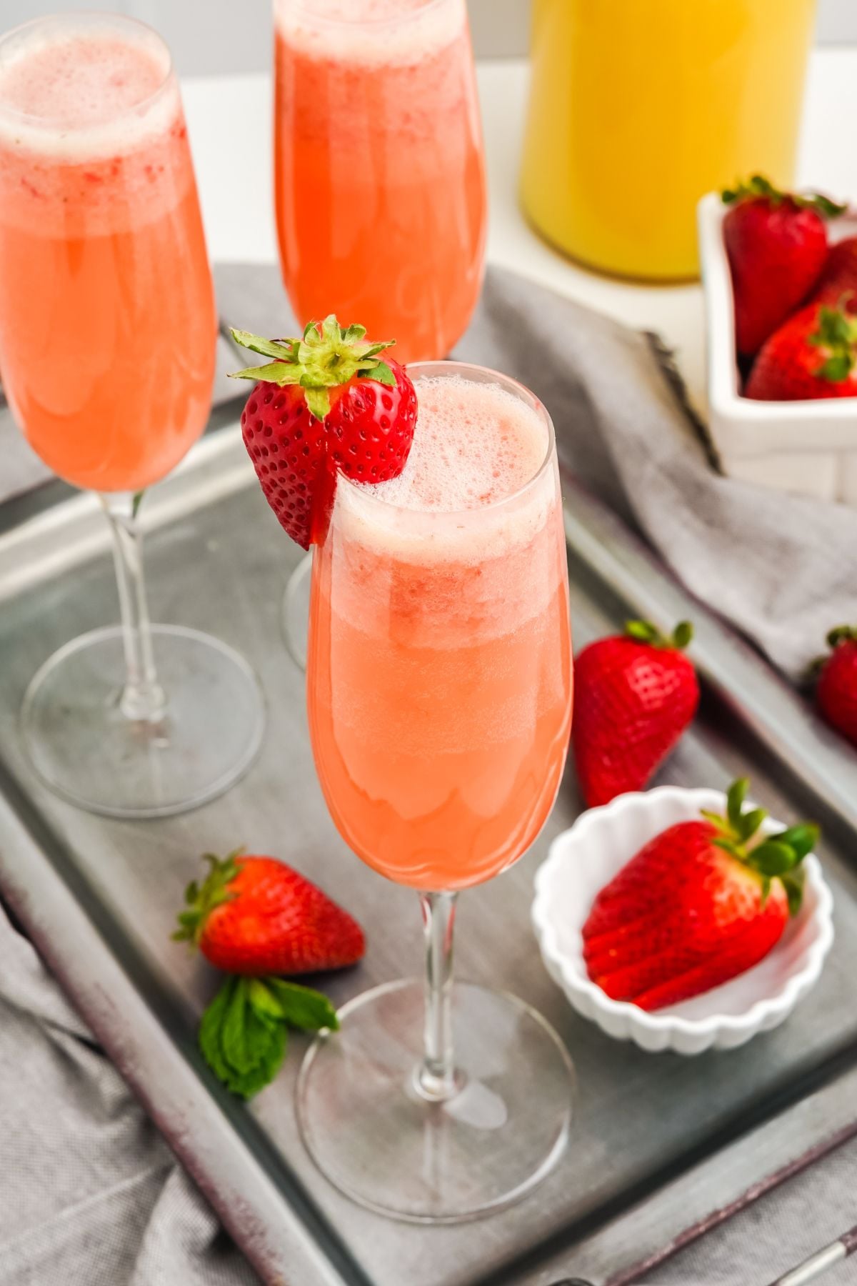 An easy strawberry mimosa in a champagne flute garnished with a fresh strawberry