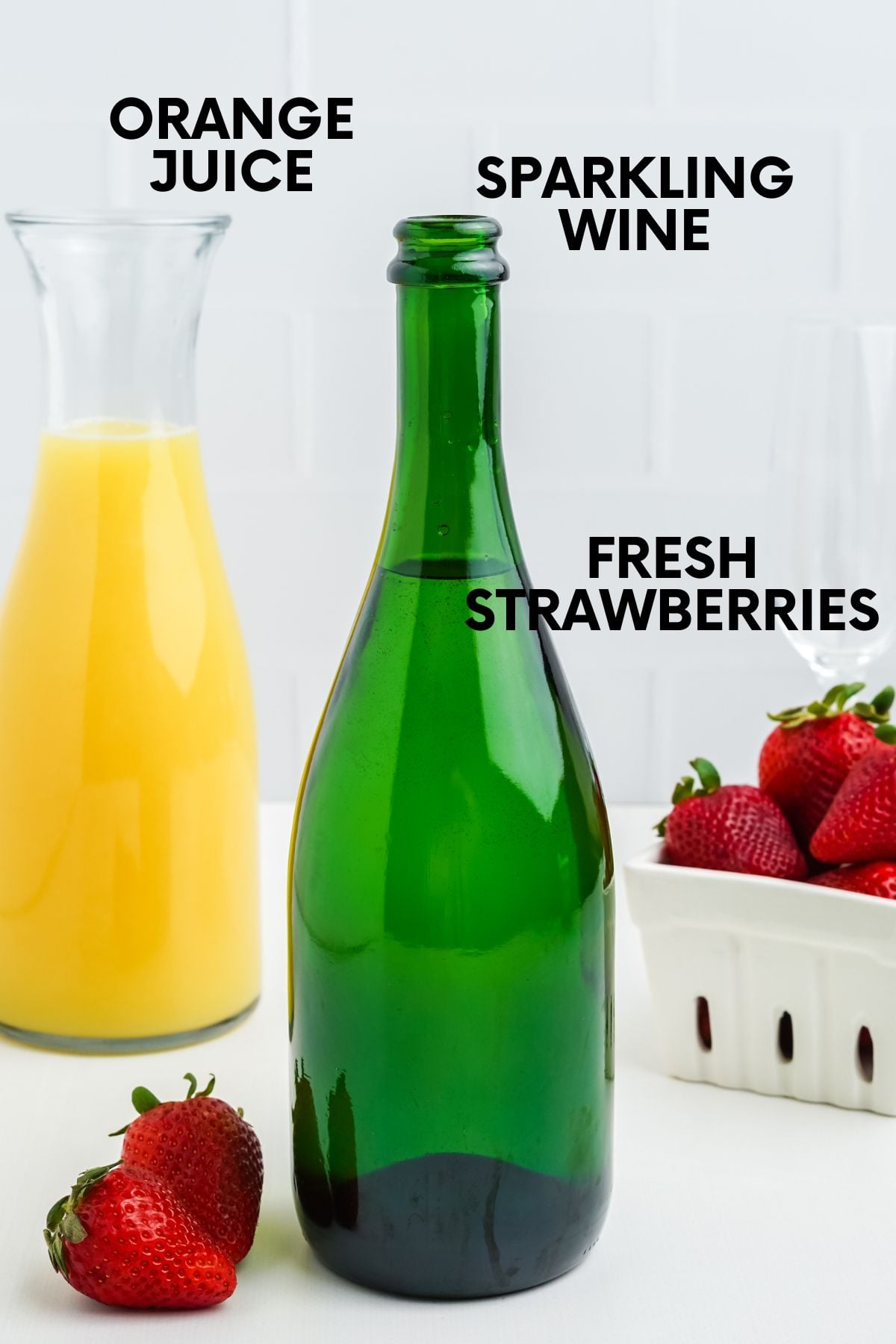 Labeled ingredients for strawberry mimosas: orange juice, sparkling wine, and fresh strawberries