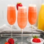 Square photo of three pink strawberry mimosas in champagne flutes