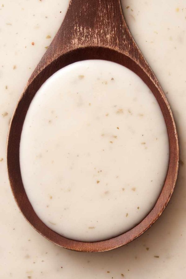 Close view of homemade caesar salad dressing in a wooden spoon.
