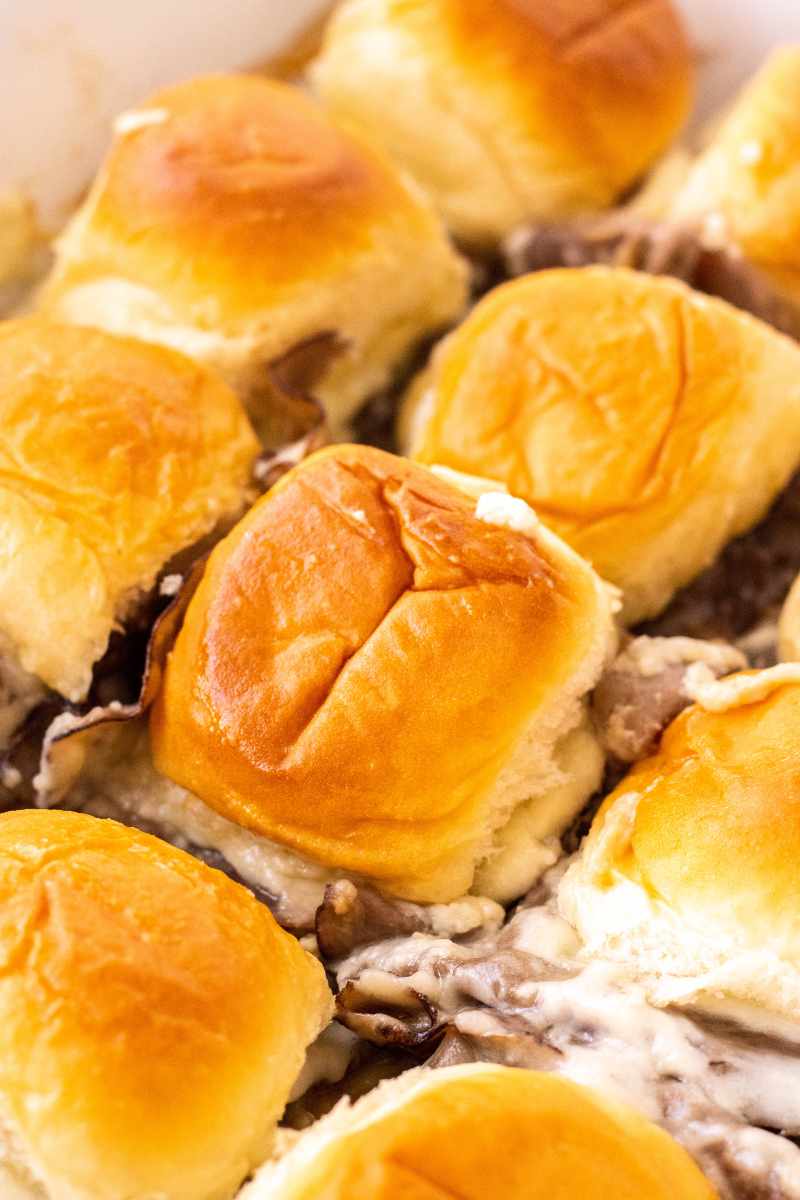 Close view of hot roast beef sliders in a baking dish.