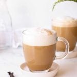 A homemade vanilla latte is dusted with a sprinkle of cinnamon on top.