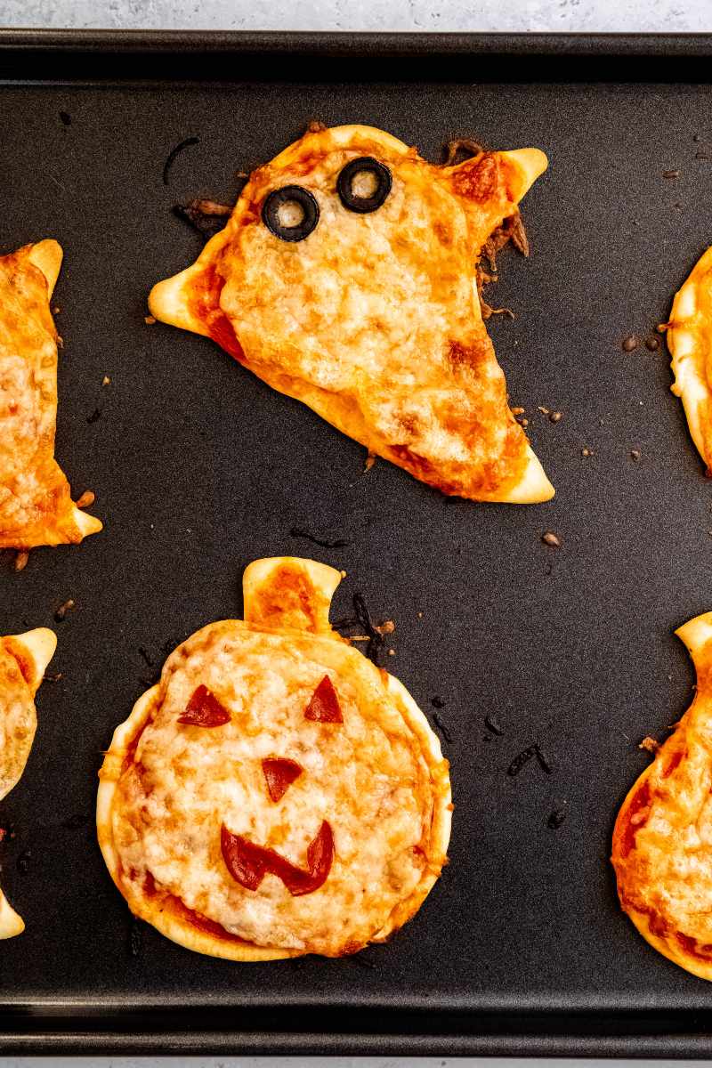 Halloween pizzas on a baking sheet.