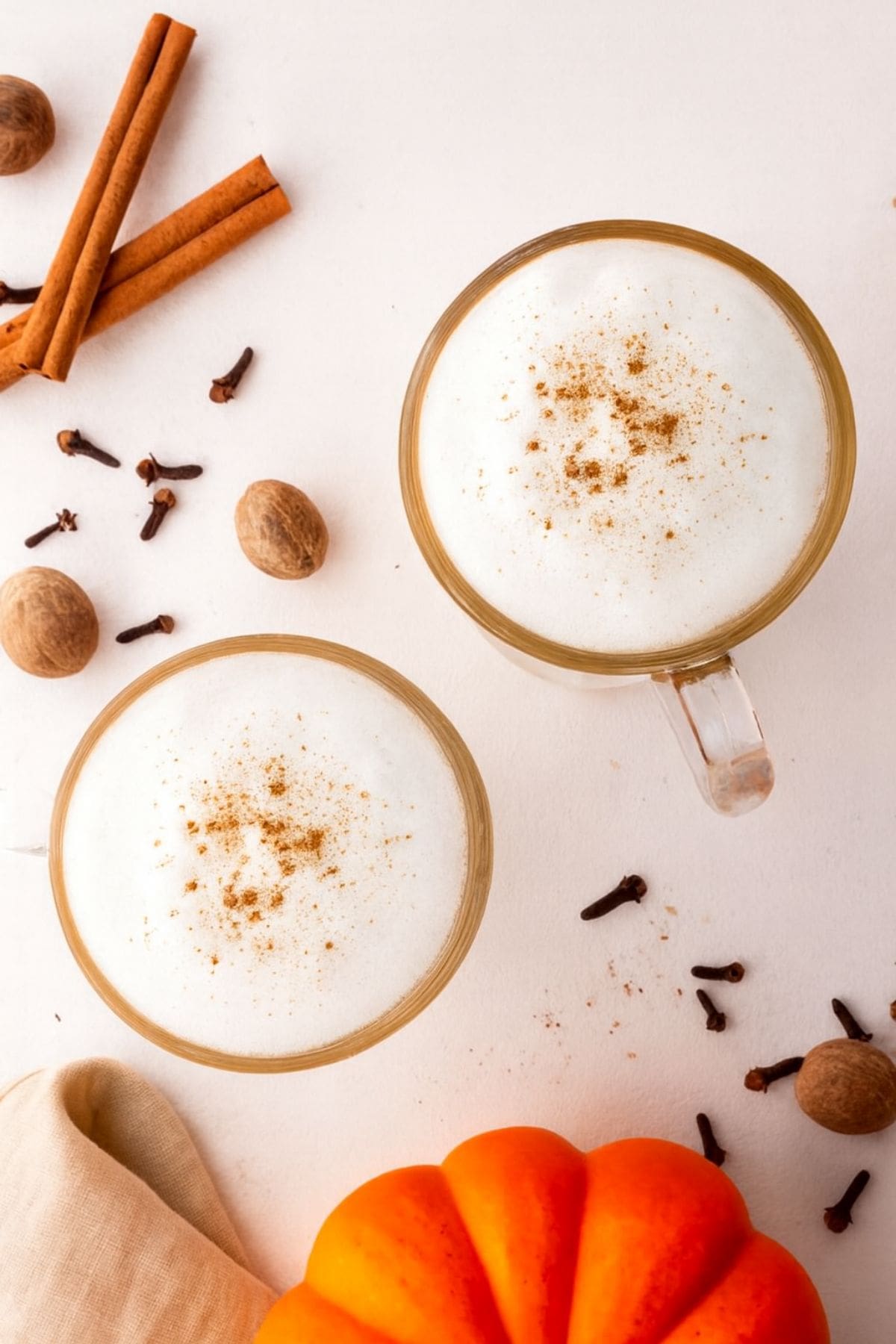 Two mugs of homemade pumpkin spice latte on a white countertop