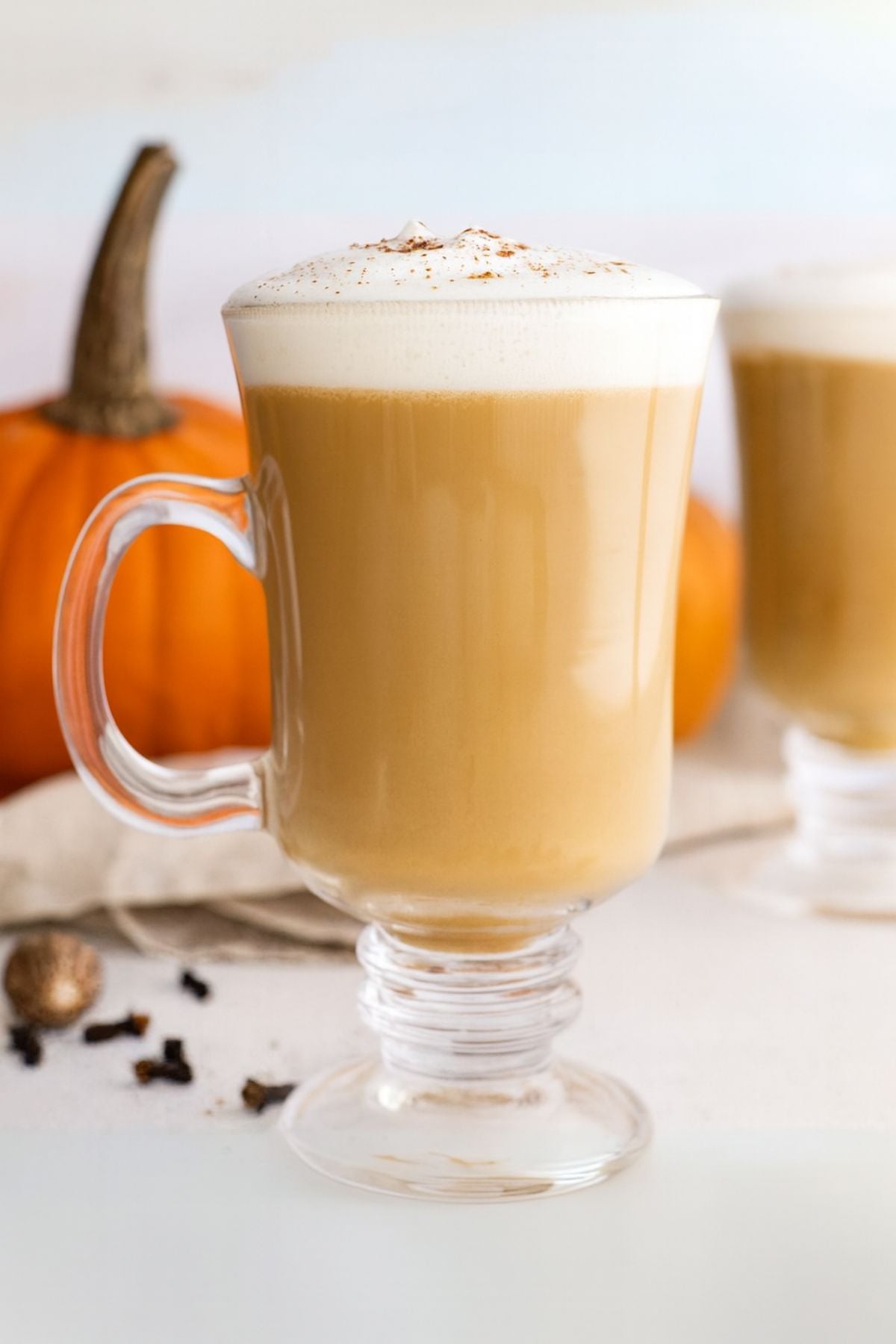 Homemade pumpkin spice latte in clear glass mugs in a white kitchen