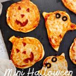 Mini halloween pizzas shaped like ghosts and jack-o-lanterns served up on a slate board. A text overlay reads, "Mini Halloween Pizzas."