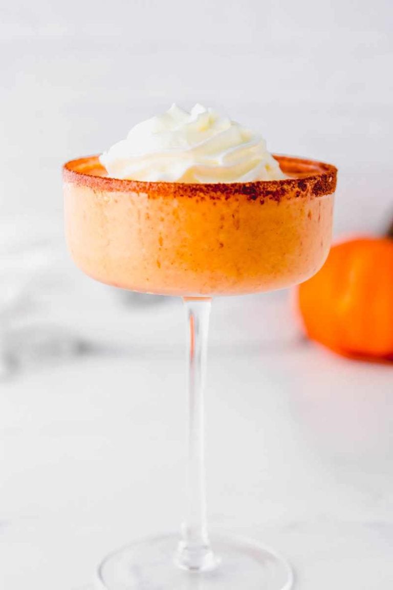 Close view of a pumpkin cocktail in a coupe glass rimmed with cinnamon and sugar.