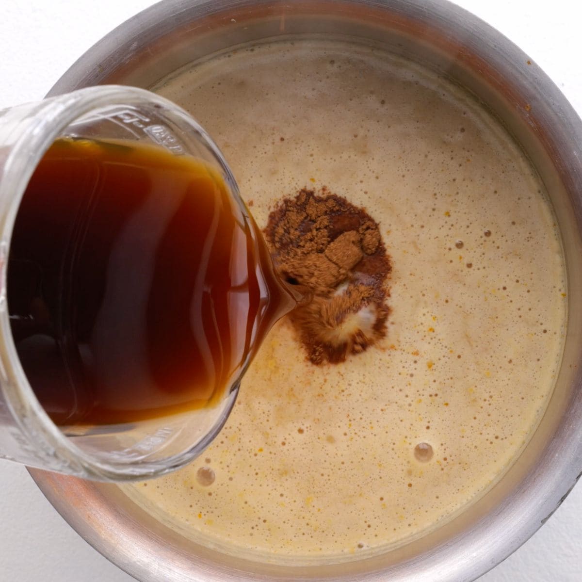 Adding coffee to a pumpkin spice latte in a saucepan