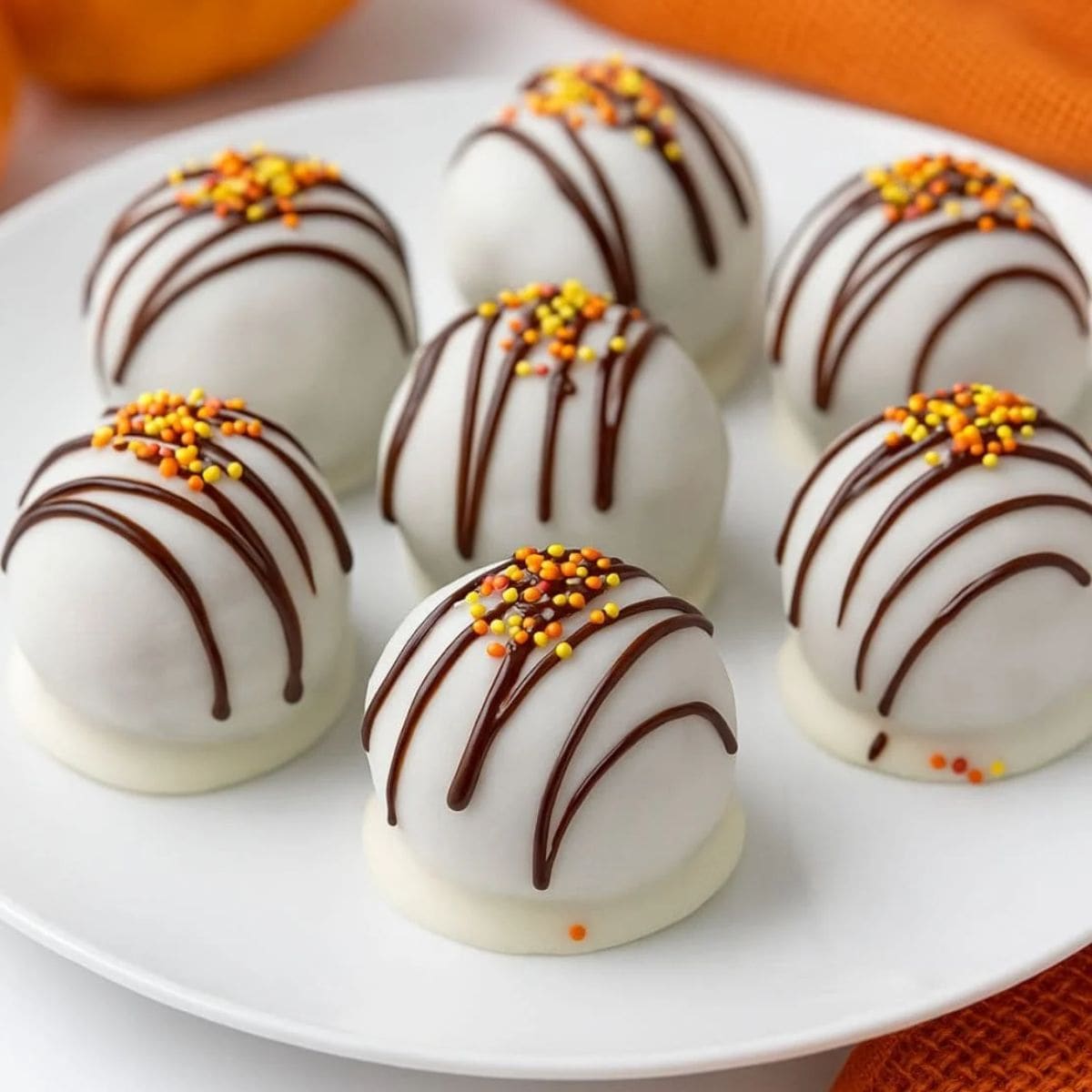 Pumpkin spice cake pops on a white plate